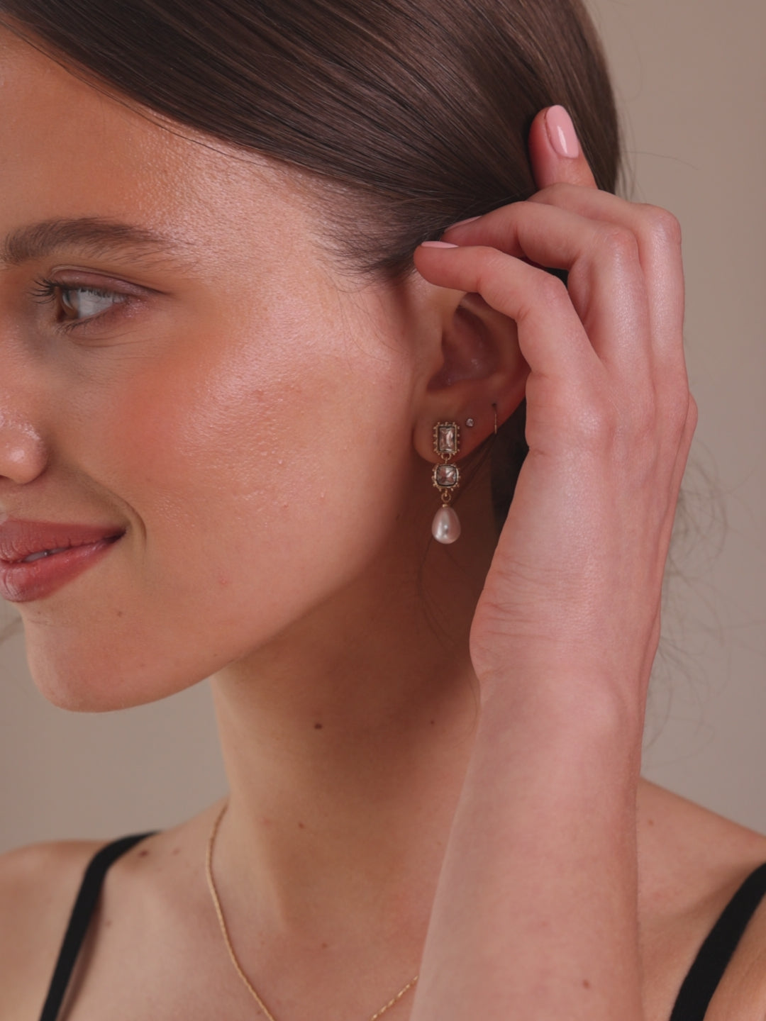 Pair of gold earrings with clear gemstones and a pearl drop